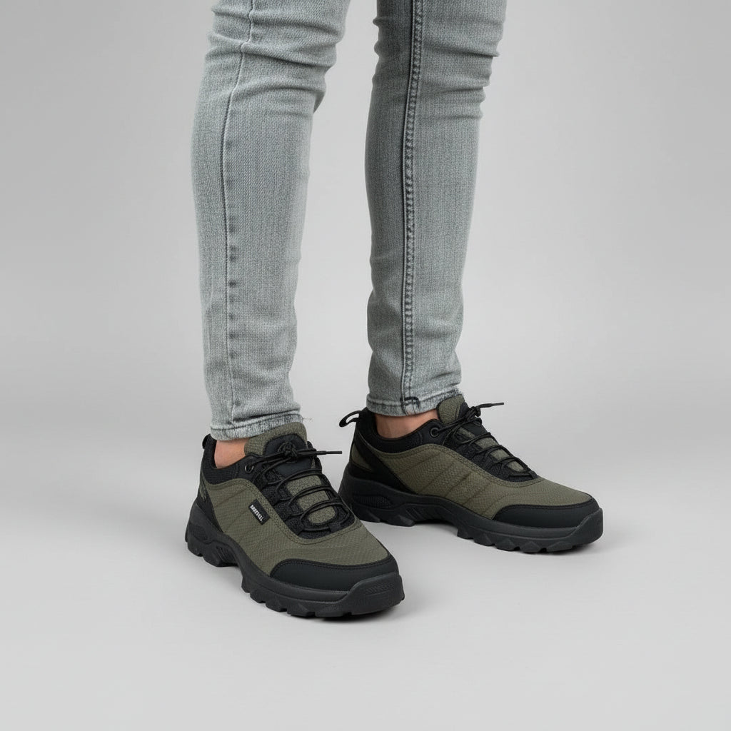 Person wearing black and gray shoes on a paved walkway with grass and trees in the background.